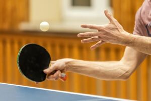 Dynamic close-up of table tennis player serving, capturing the motion and focus of the game.